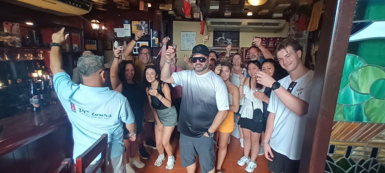 Group of tourists enjoying a rum-tasting experience during a Havana city tour in a local bar.