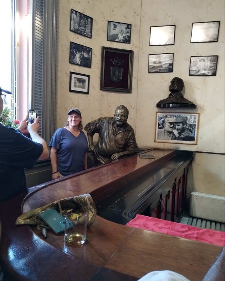 Hemingway Cuba Tour guest posing with Ernest Hemingway statue at El Floridita bar in Havana
